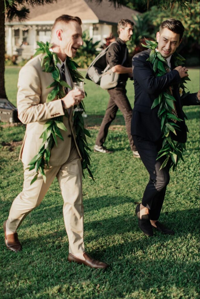 two men chatting and wearing leis at a Maui wedding