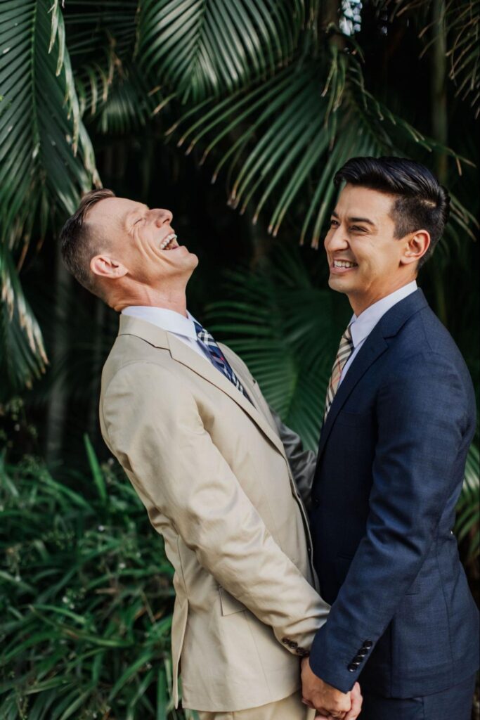 two grooms laughing while holding hands