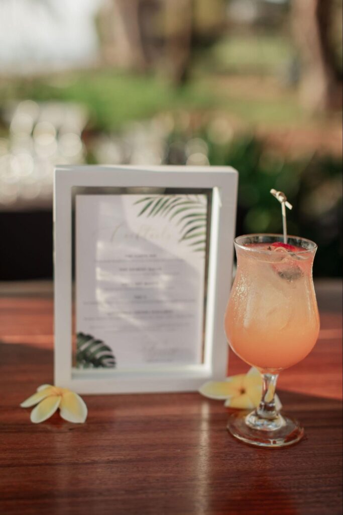 a signature cocktail next to a cocktail sign at a Maui wedding