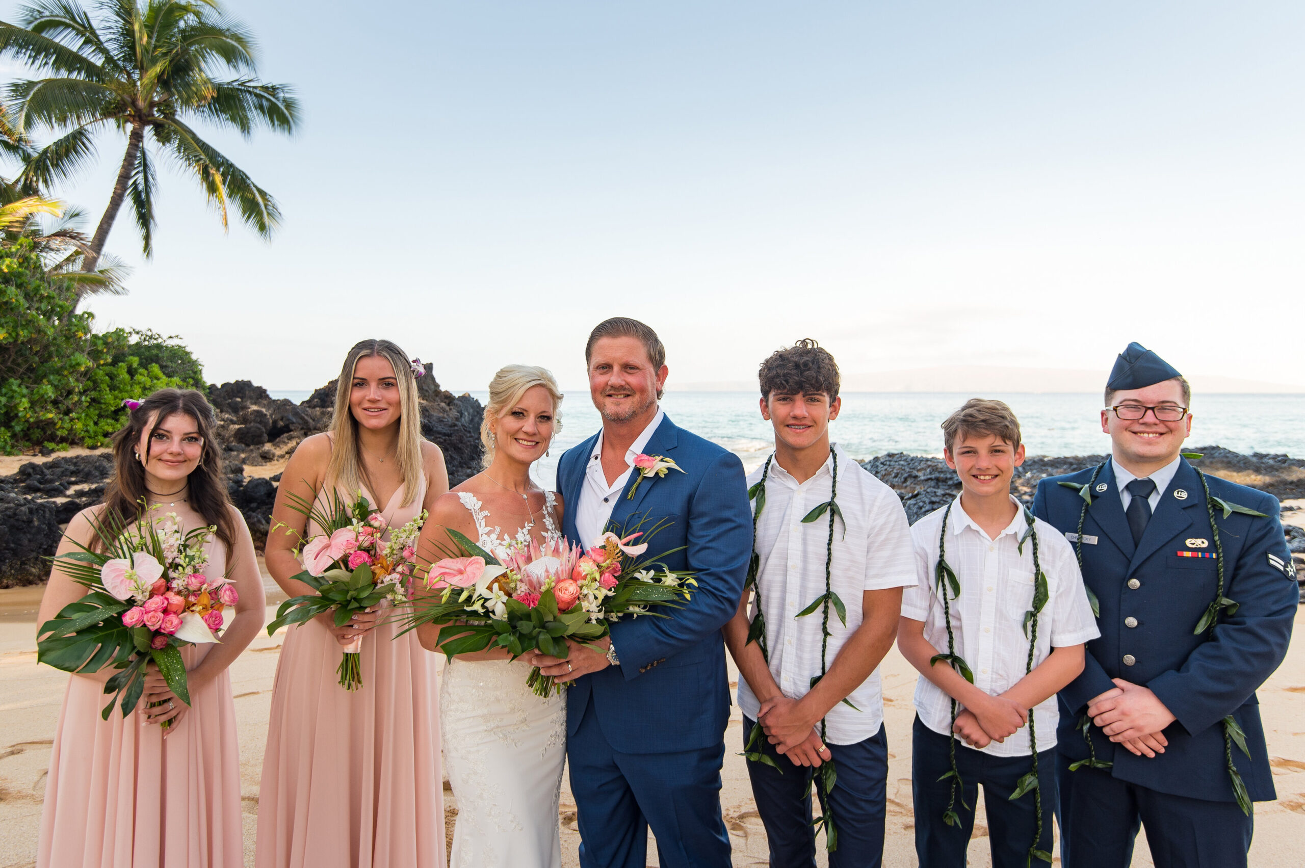 family posing for wedding party photos on the beach in Maui