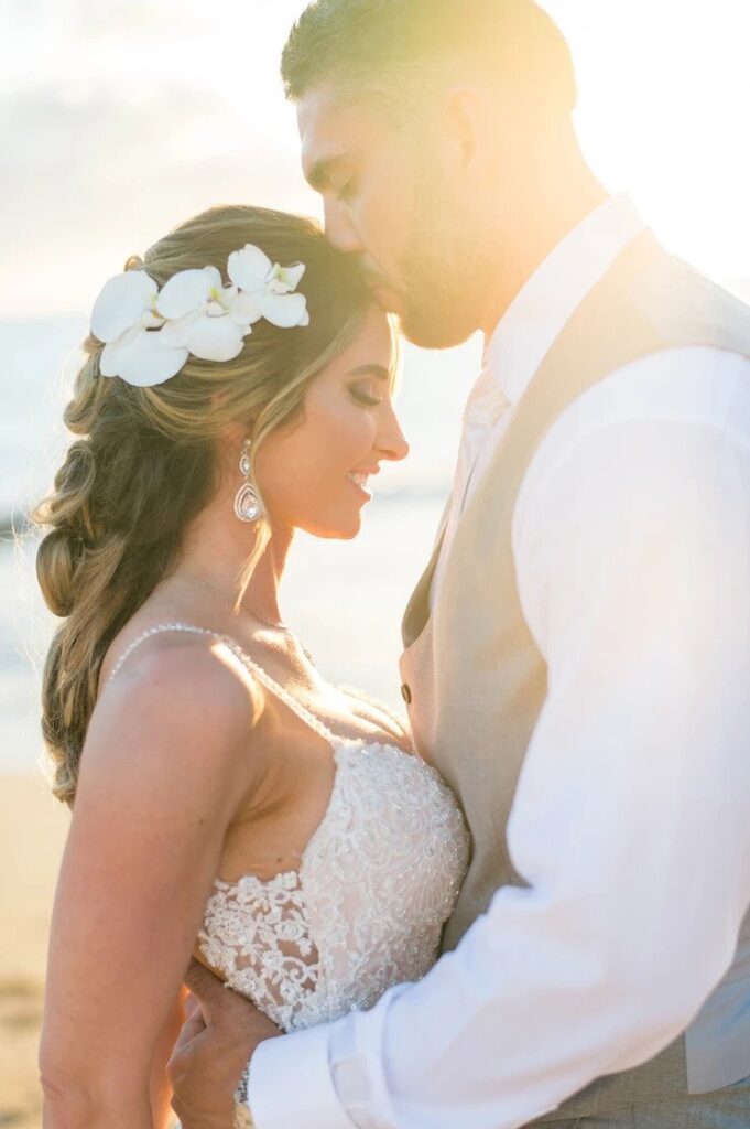 groom kisses his bride on the forehead at their Maui beach wedding