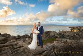 newlyweds pose on rocks looking out to the ocean in Maui