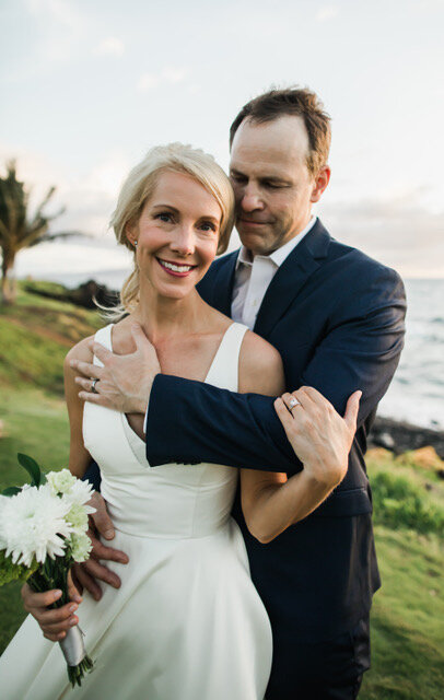 newlyweds embrace overlooking Maui ocean