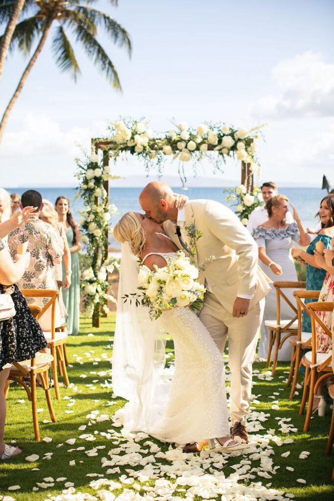 groom dips bride for kiss on ceremony aisle