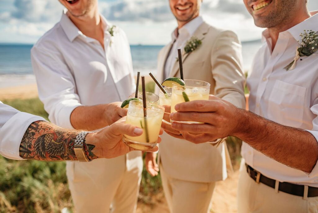 groomsmen cheers cocktails on the beach